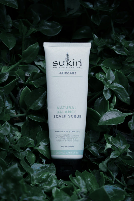 a tube of sukin natural scalp scrub sitting in a bush