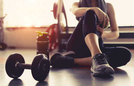 woman taking a break at the gym, sitting down and having a drink