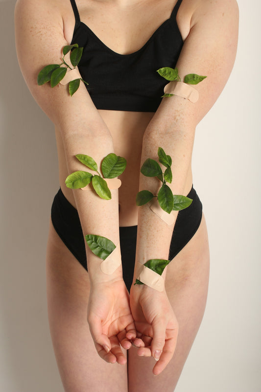 a woman in a black bikini with green leaves on her arms