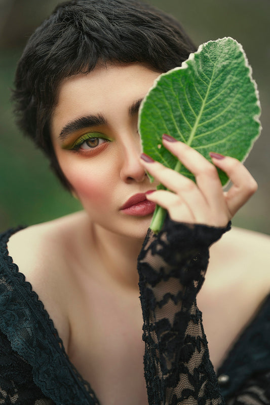 a woman holding a leaf over her face
