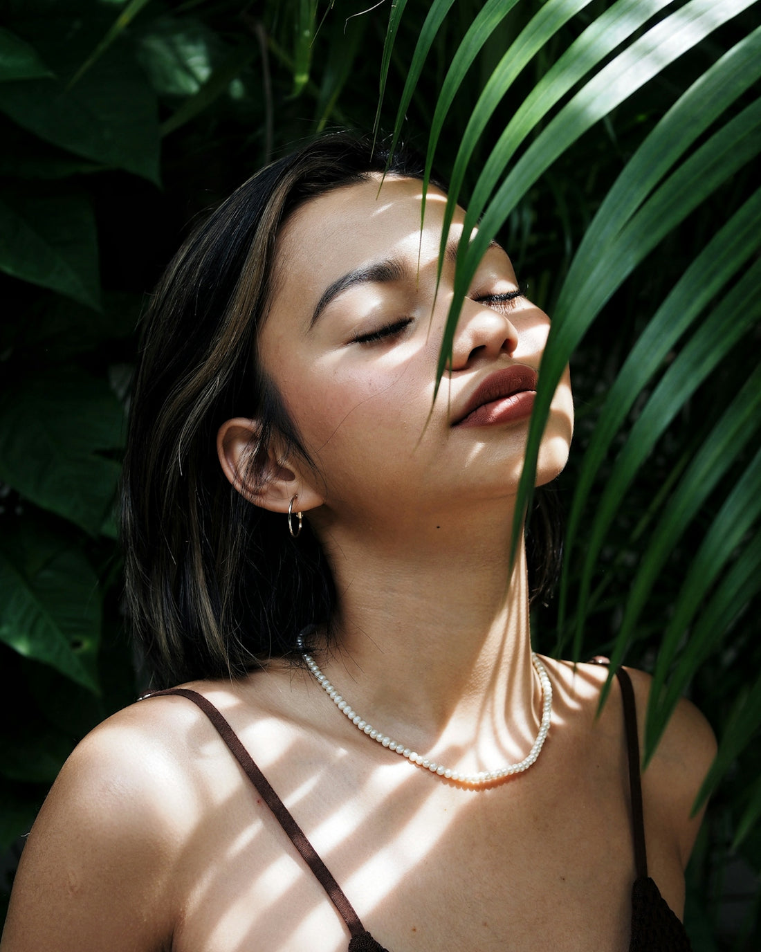 a woman with her eyes closed and a necklace on