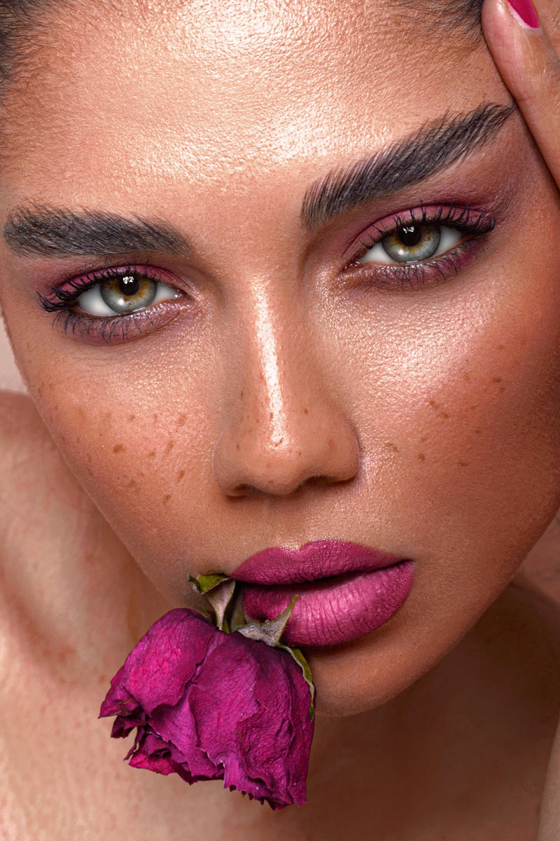 a close up of a woman with a rose in her mouth