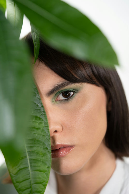 a woman with a green eyeliner and a leaf