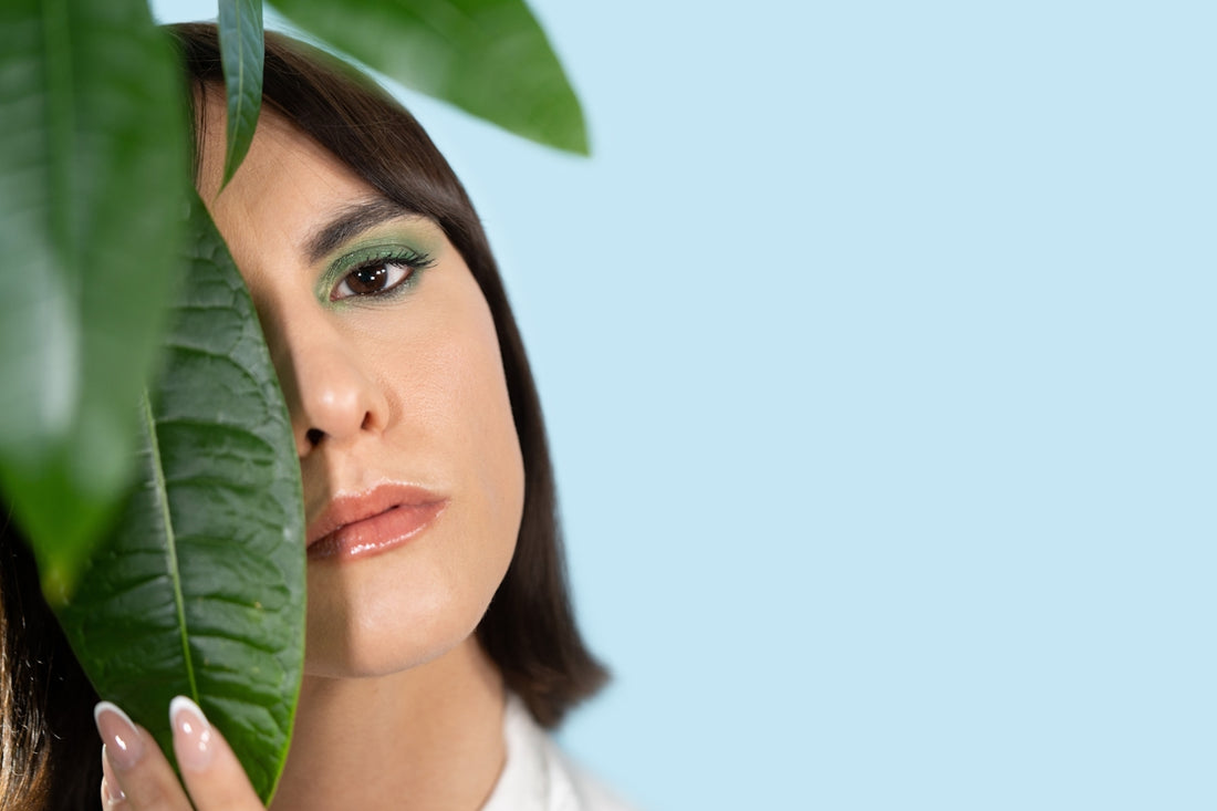 a woman holding a green leaf over her face