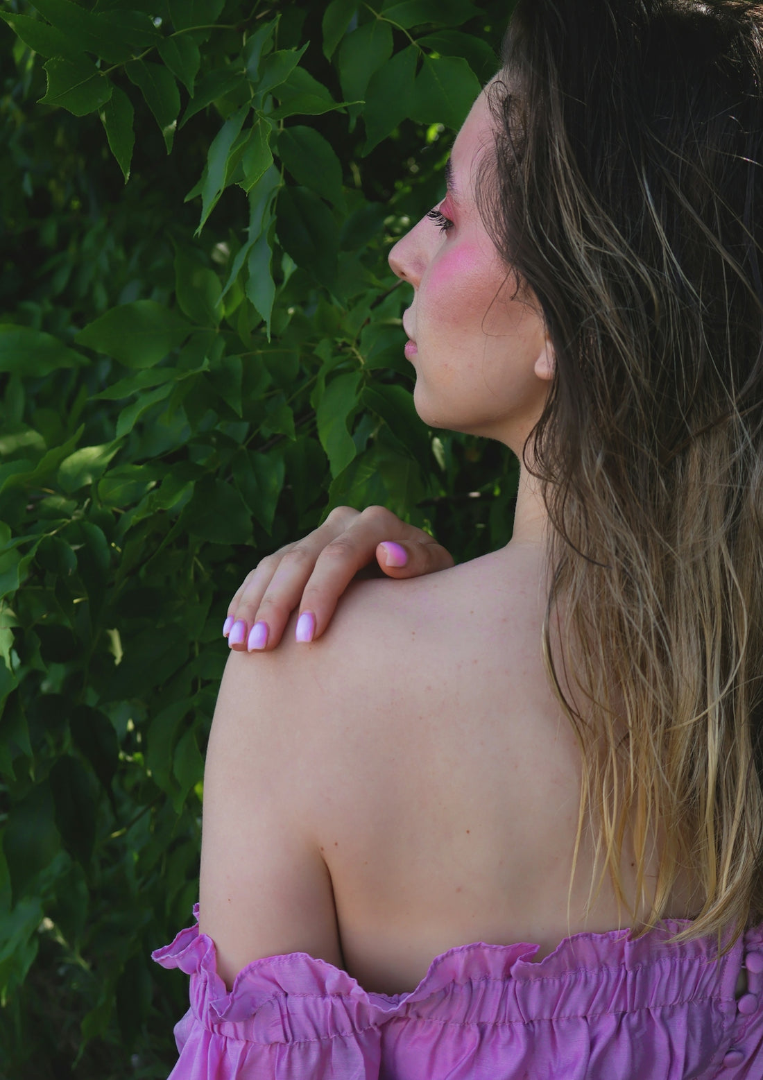 a woman in a purple dress standing in front of a bush