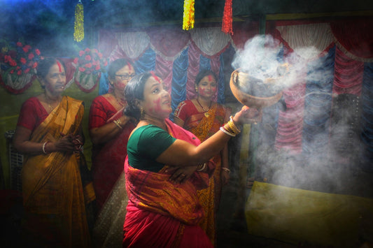 a woman in a red and yellow sari holding a pot