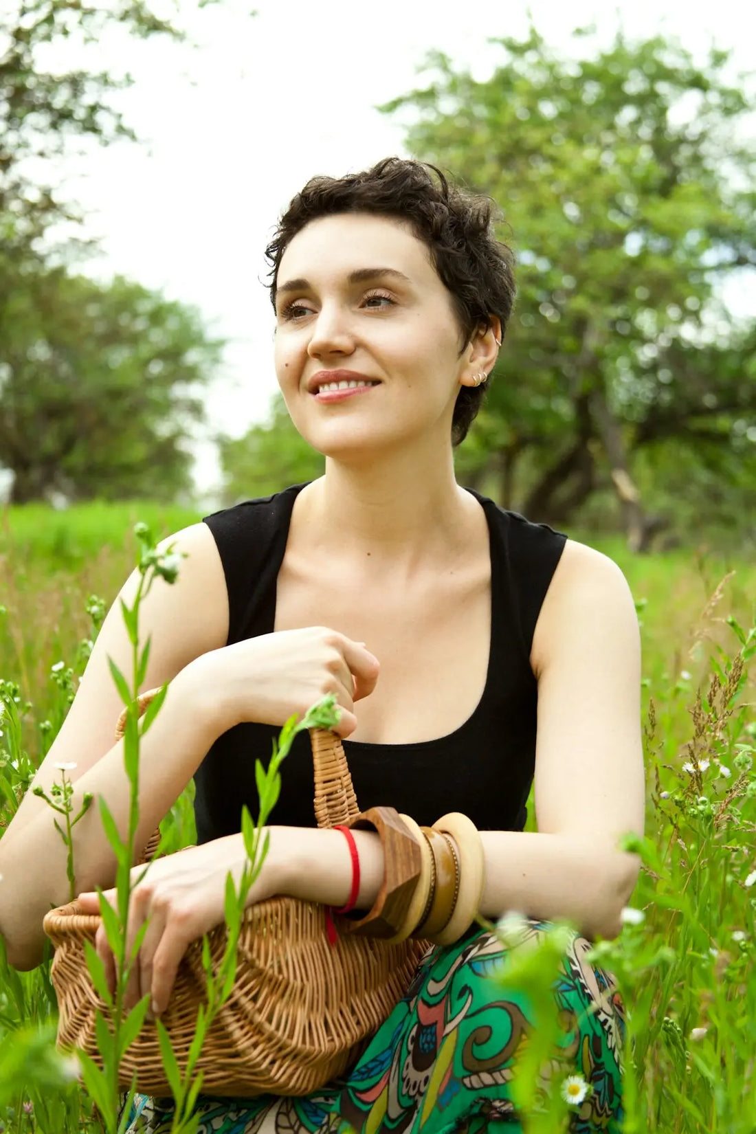 A woman sitting in the grass with a basket