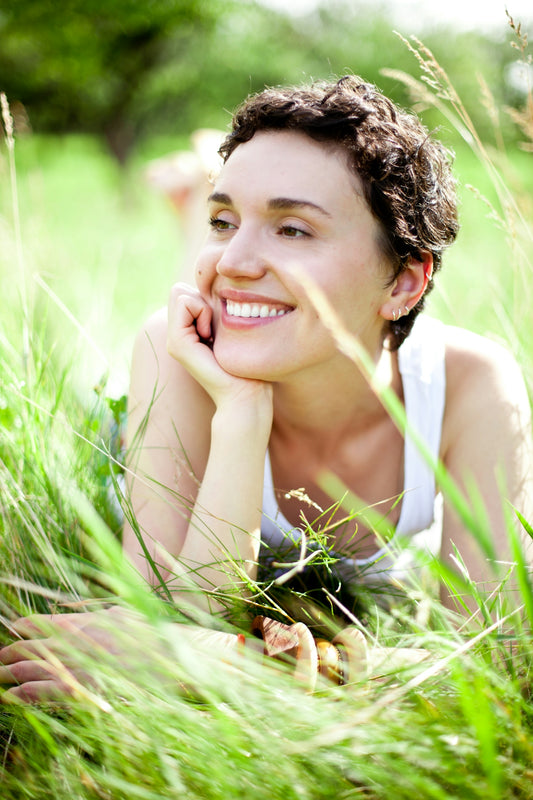 A woman laying in the grass with her hand on her chin