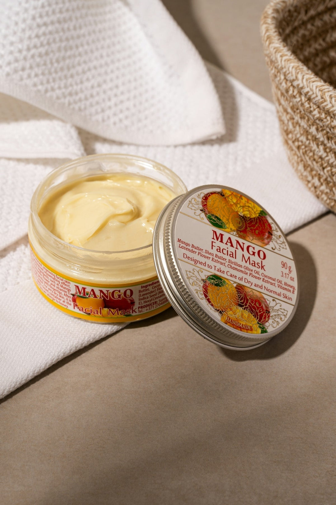 A jar of mango butter sitting on a towel next to a basket