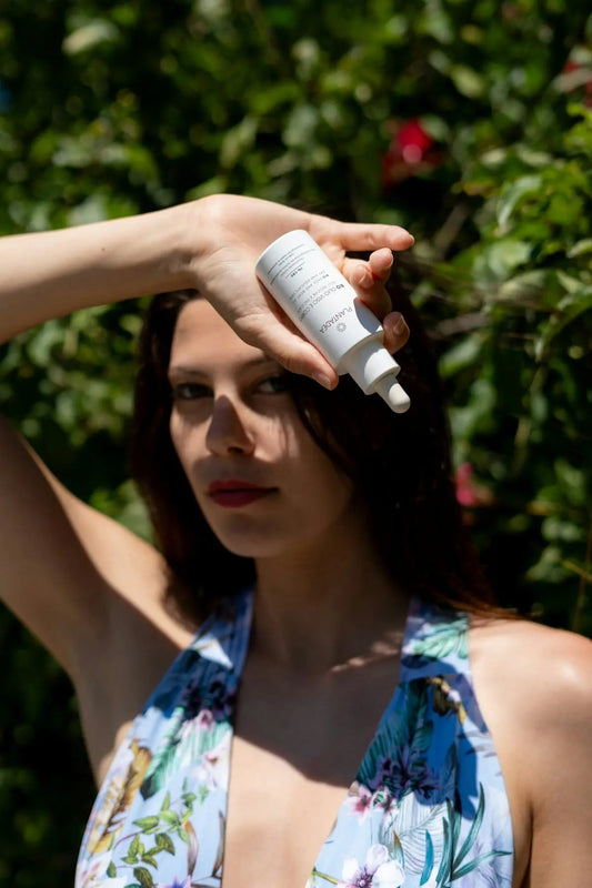 Woman holds skincare product in front of her.