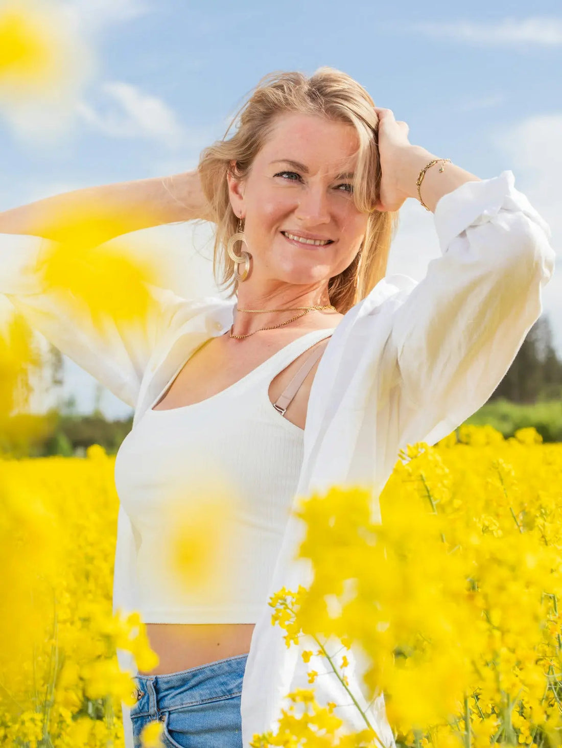 Beautiful woman smiles amidst a field of yellow flowers.