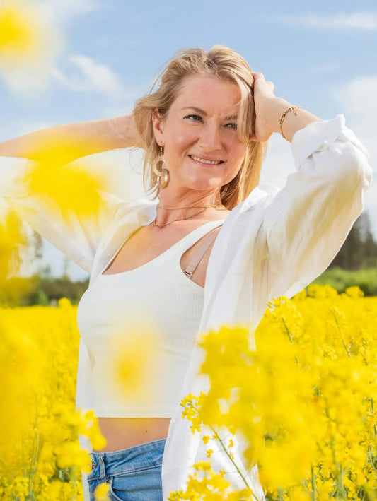 Beautiful woman smiles amidst a field of yellow flowers.