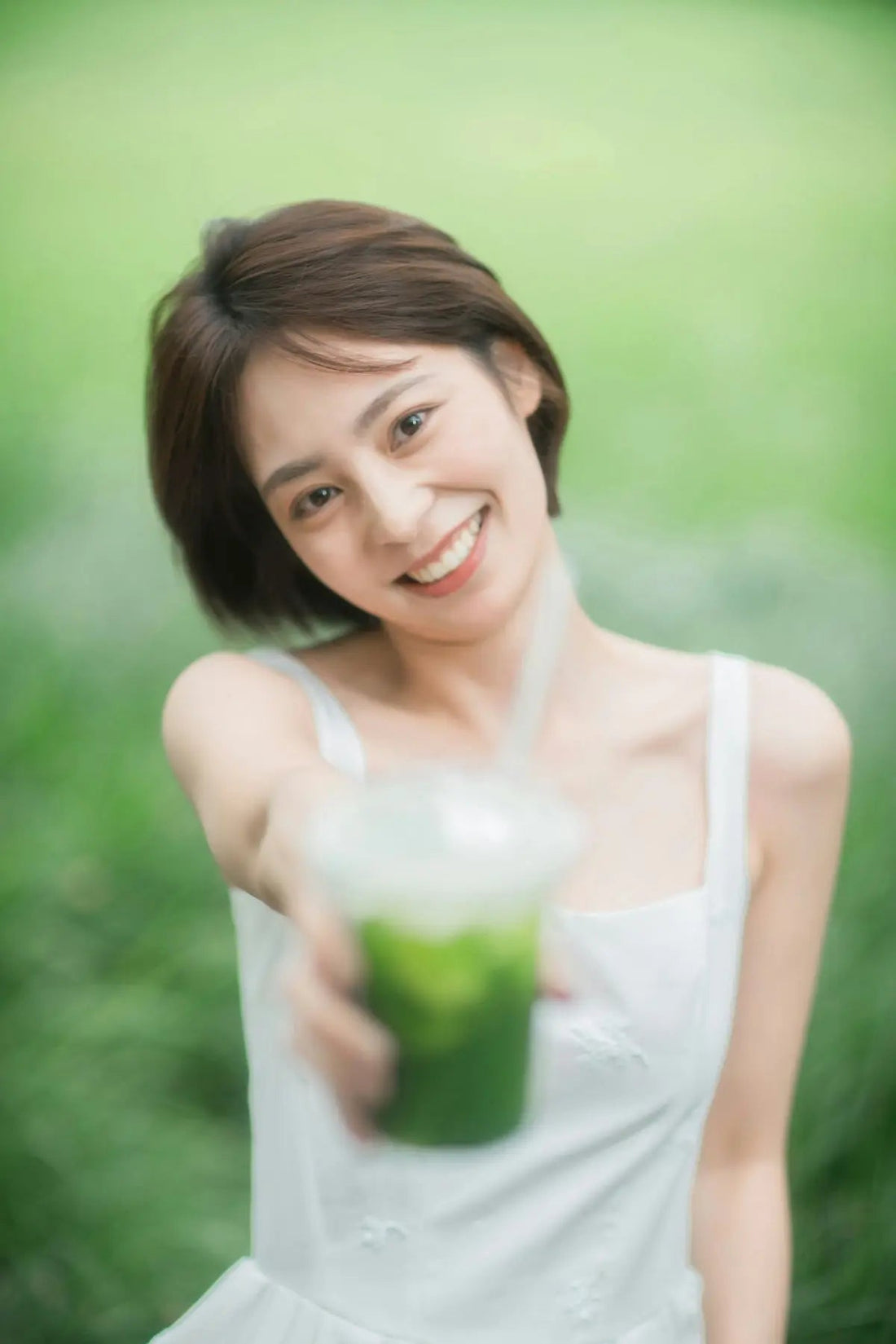 Happy woman offers a green drink.