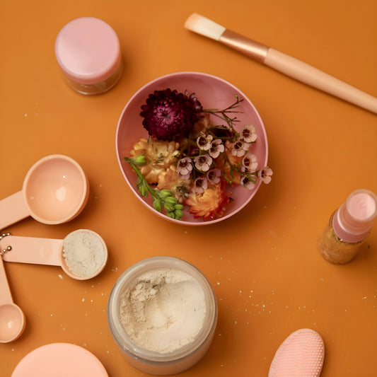 Cosmetic ingredients and tools arranged on an orange surface.