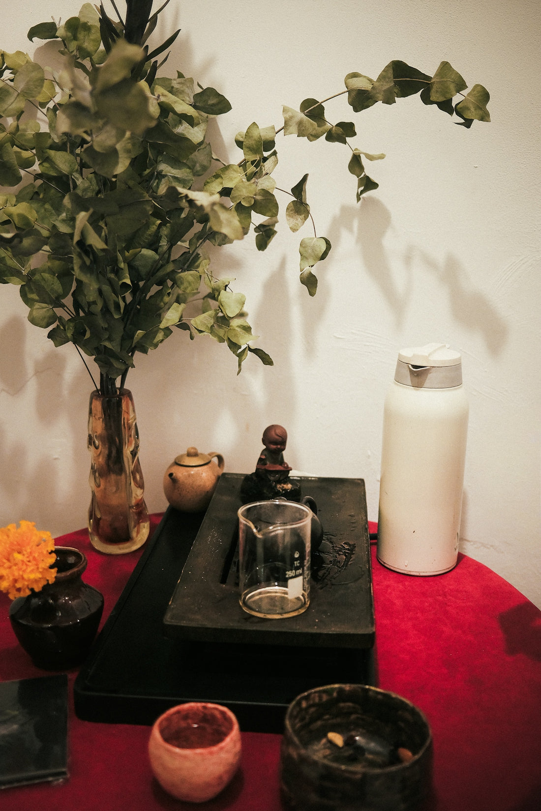 Still life with vase, beaker, and bottle on red tablecloth