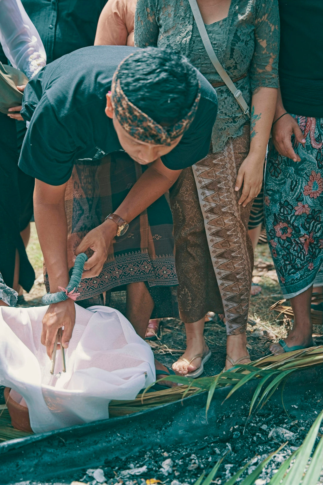 Man in traditional attire pours liquid over offerings