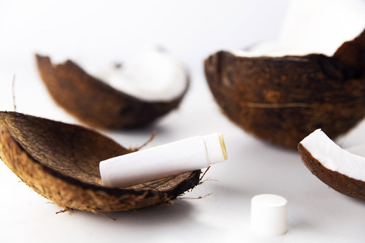 Lip balm in coconut shell halves on white background