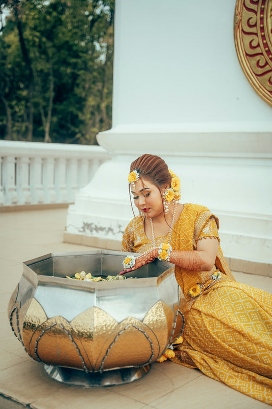 Woman in yellow traditional dress interacting with flowers.