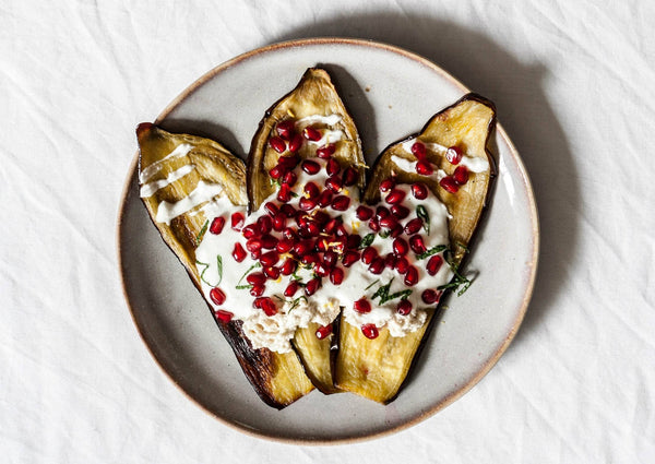 Healthy Vegan Eggplant and Tahini Bake with pomegranate and a garlic dip in a dish on a table